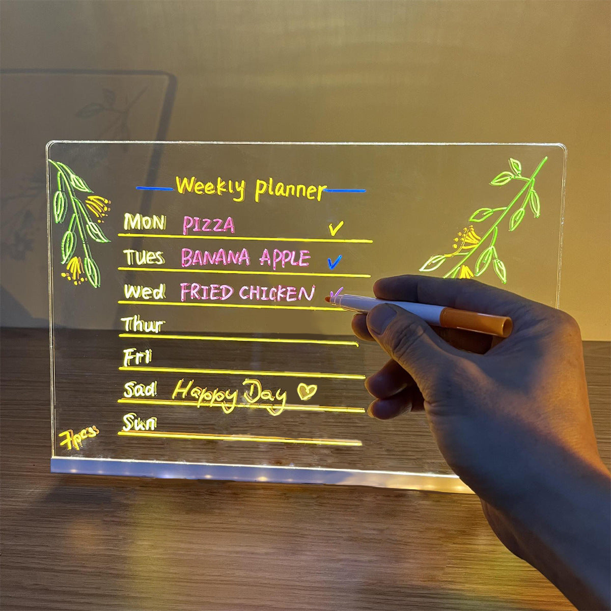 LED light-up writing board displaying a colorful weekly planner with handwritten notes on acrylic surface.