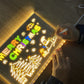 Person writing on LED light-up writing board with Christmas decorations and colorful lights.